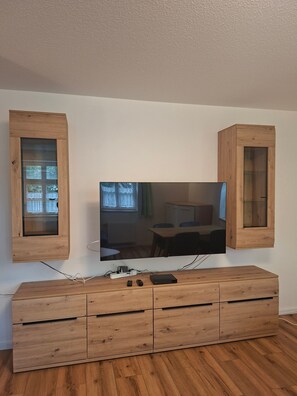 Een flatscreen televisie aan een wand bevestigd, met houten kasten aan weerszijden.