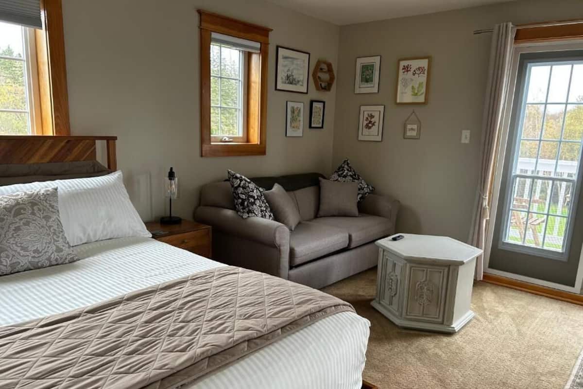 A bedroom with a bed, a sofa, a nightstand, and a side table.