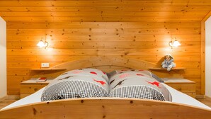 A wooden-paneled room with a bed, two bedside tables, and wall-mounted lamps. - Apartment 'Ju' with Mountain View, Shared Pool and Wi-Fi (San Martino In Badia)