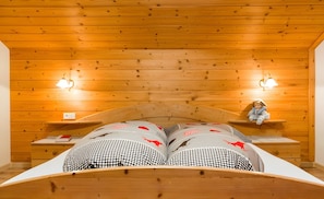 Ein Zimmer mit Holzwänden, einem Bett, zwei Nachttischen und Wandlampen.