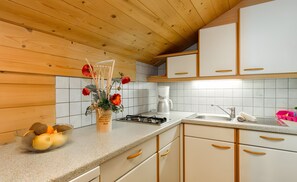 Eine Küche mit Holzschränken, einem Gasherd, einer Kaffeemaschine und einer Schüssel Obst.