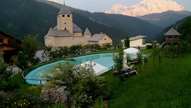 A church with a bell tower, a swimming pool, and a view of mountains. - Apartment 'Ju' with Mountain View, Shared Pool and Wi-Fi (San Martino In Badia)