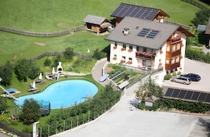 Ein großes Gebäude mit Schwimmbad, Solaranlage und einem eingezäunten Bereich inklusive Rutsche.