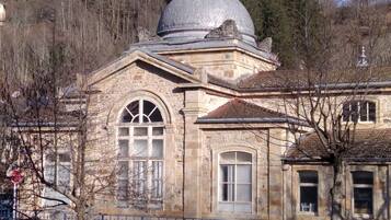 A stone building with a dome, arched windows, and a stone fence.