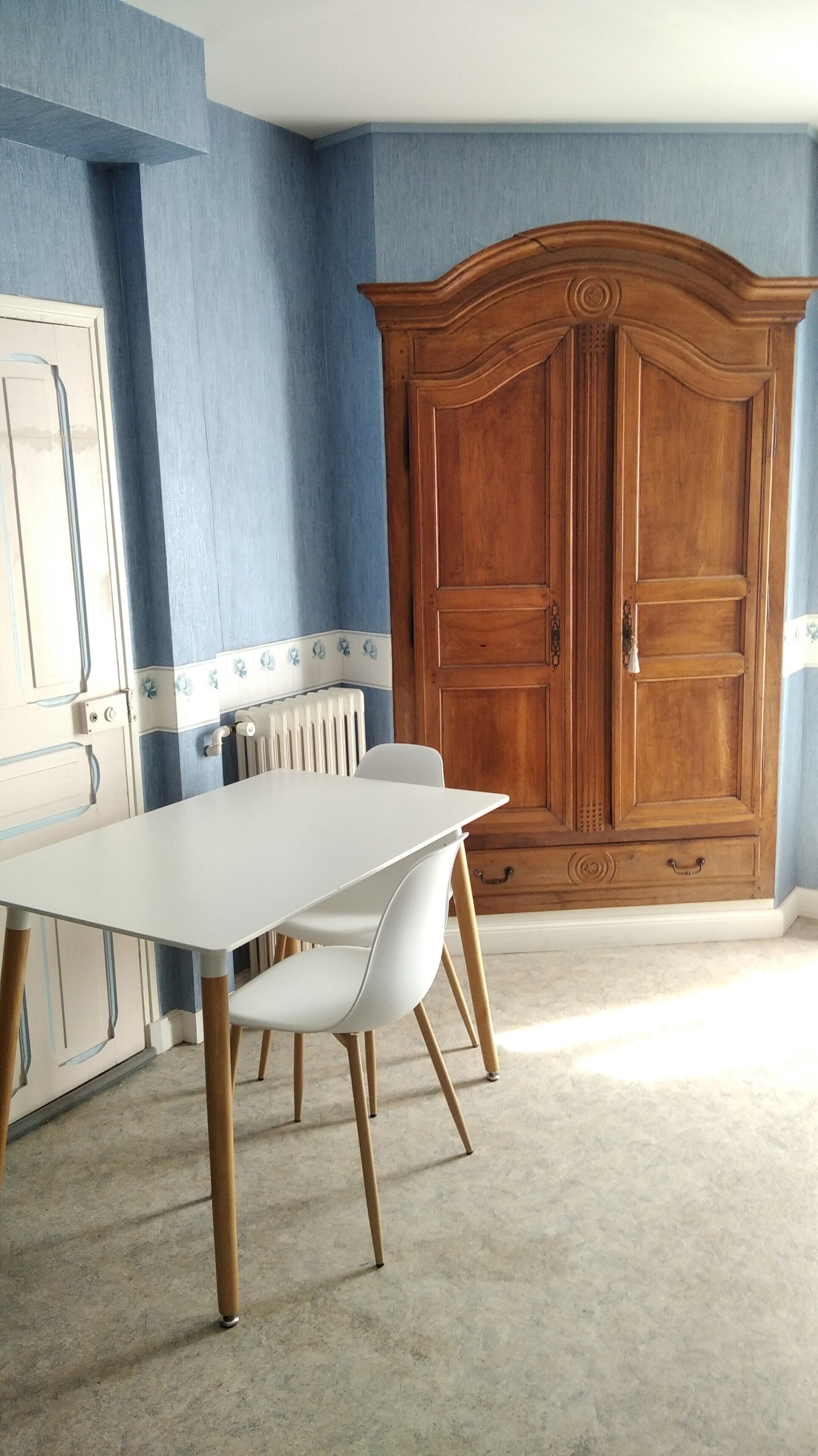 A dining area with a white table and chairs, a wooden cabinet, and blue walls.