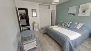 Ein Schlafzimmer mit Bett, kleinem Tisch, Stuhl, Kleiderschrank und Spiegel.