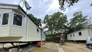 A mobile home with satellite dish, a red umbrella, and a tree in the background. - Cabin Sleeps 6 With Garden and Pets Welcome (Cowes)