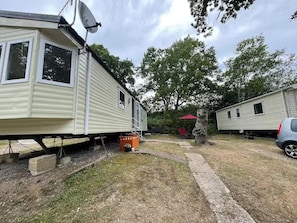 En husvagn med en satellantenn, ett rött parasoll och ett träd i bakgrunden.