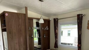 A cozy seating area with a round table, cushioned benches, and a window with curtains. - Cabin Sleeps 6 With Garden and Pets Welcome (Cowes)