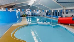 An indoor swimming pool with a blue and white color scheme, a diving board, and a red slide. - Cabin Sleeps 6 With Garden and Pets Welcome (Cowes)
