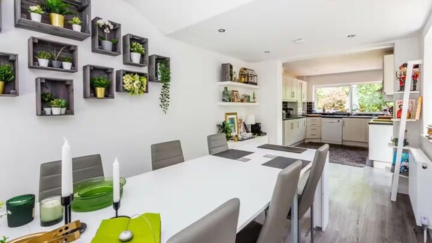 A modern kitchen with white cabinets, a dining area with a white table and chairs, and a kitchen island.