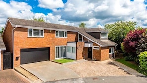 A two-story residential building with a garage, a driveway, and a well-maintained lawn.