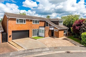 A two-story residential building with a garage, a driveway, and a well-maintained lawn.