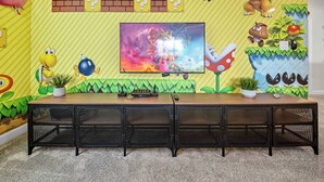 Ein Mario-Themenzimmer mit einem langen Tisch, einem Fernseher und verschiedenen Dekorationen.