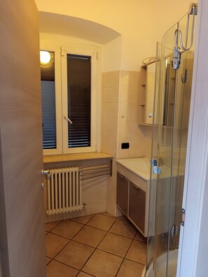 A bathroom with a window, a radiator, a sink, and a glass shower enclosure. - Apartment 'Unit 3' with Wi-Fi and Air Conditioning (Como)