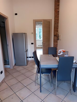 A compact kitchen with a refrigerator, a dining table with chairs, and a view through an open door to a balcony. - Apartment 'Unit 3' with Wi-Fi and Air Conditioning (Como)