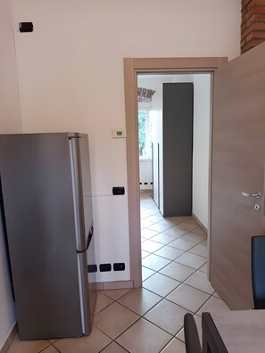 A kitchen with a refrigerator, a door leading to a balcony, and a tiled floor. - Apartment 'Unit 3' with Wi-Fi and Air Conditioning (Como)