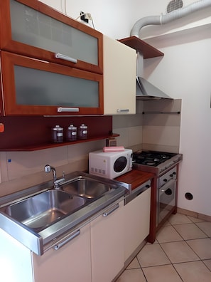 A kitchen with a stainless steel sink, a microwave, a gas stove, and wooden cabinets. - Apartment 'Unit 3' with Wi-Fi and Air Conditioning (Como)