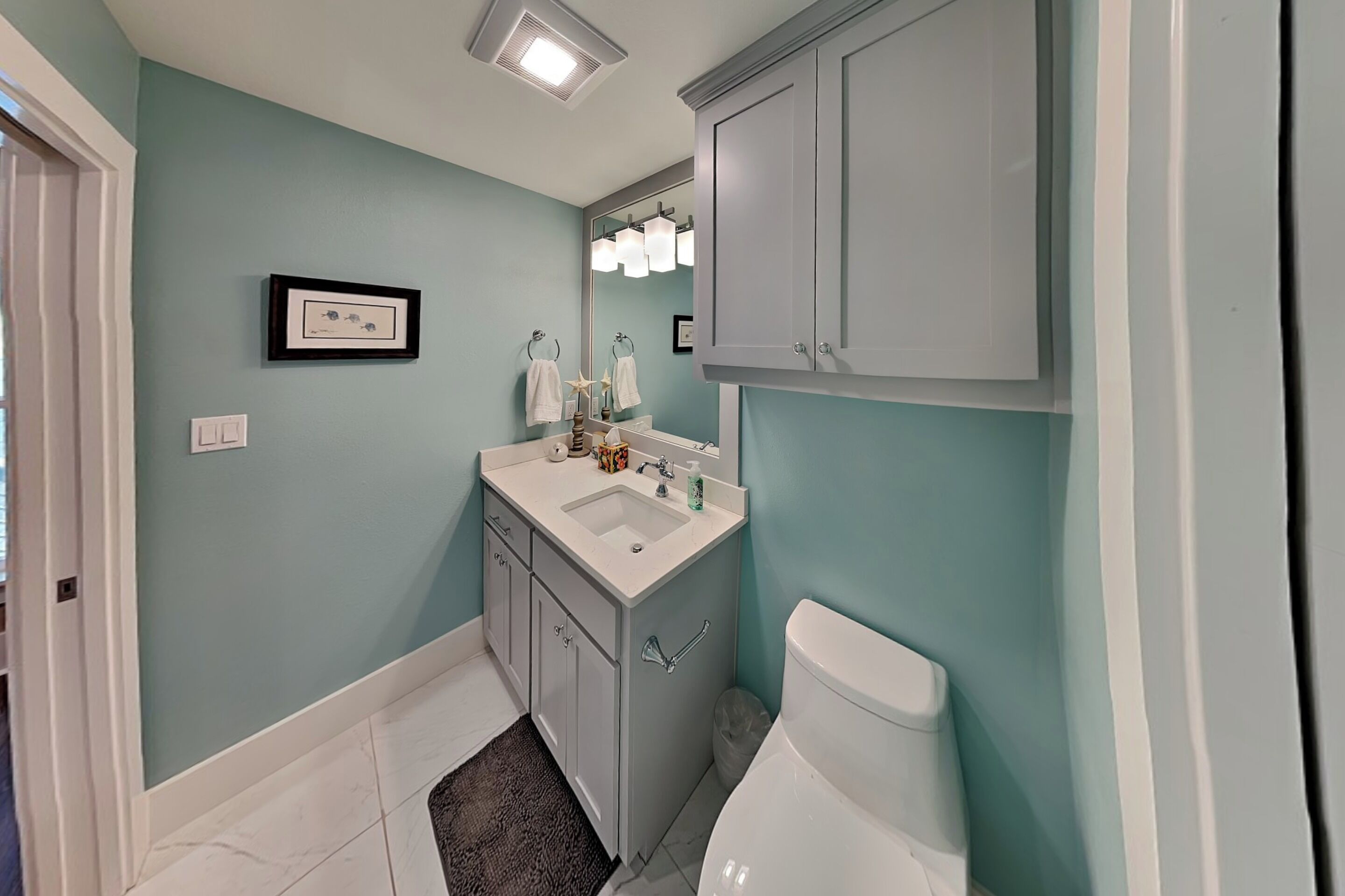 Une salle de bain avec un lavabo, un miroir et des toilettes.