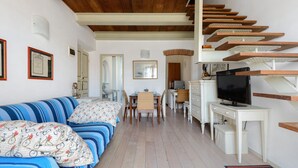 Una habitación con una cama, un escritorio, un televisor y una escalera.