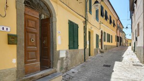 Una estrecha calle adoquinada con edificios amarillos, puertas de madera y contraventanas verdes.