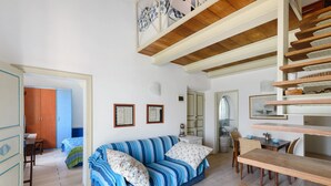 Una habitación con un sofá a rayas, un banco de madera y una escalera.