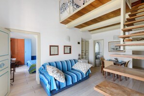 Una habitación con un sofá a rayas, un banco de madera y una escalera.