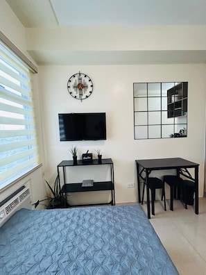 A bedroom with a bed, a TV, a desk, and a mirror. - Studio at Urban Deca Towers Cubao (Quezon City)