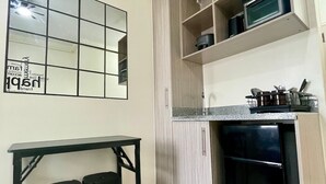 Une cuisine compacte comprenant un plan de travail, un réfrigérateur et une étagère fixée au mur.