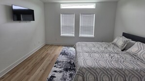 Camera da letto con un letto, una ventola a soffitto, una TV a parete e due finestre con persiane.
