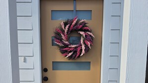 Una porta d'ingresso con una ghirlanda, una finestra verticale e una cassetta delle lettere.