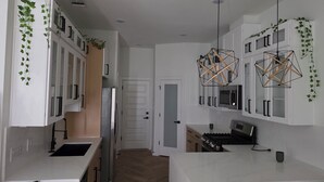 Una cucina moderna con mobili bianchi, un frigorifero in acciaio inox, un forno integrato e un piano cottura a gas.