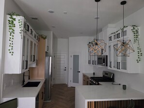 A modern kitchen with white cabinetry, a stainless steel refrigerator, a built-in oven, and a gas stove. - Pleasant 3-bedroom house with AC in vibrant Houston (Houston)
