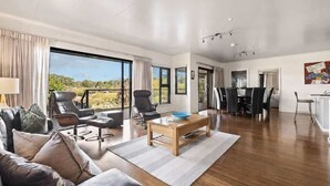A spacious living room with a large window, a dining area, and a kitchen. - Charlie Bravo Chalet—Escape to the Golden Triangle (Margaret River)