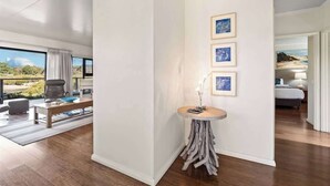 A modern interior with a wooden floor, a round table with a vase, and framed pictures on the wall. - Charlie Bravo Chalet—Escape to the Golden Triangle (Margaret River)