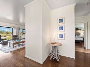 A modern interior with a wooden floor, a round table with a vase, and framed pictures on the wall. - Charlie Bravo Chalet—Escape to the Golden Triangle (Margaret River)