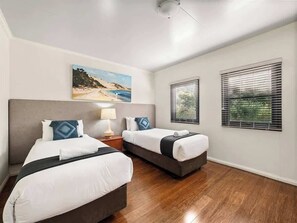 A hotel room with two beds, a painting of a beach, and two windows with blinds. - Charlie Bravo Chalet—Escape to the Golden Triangle (Margaret River)