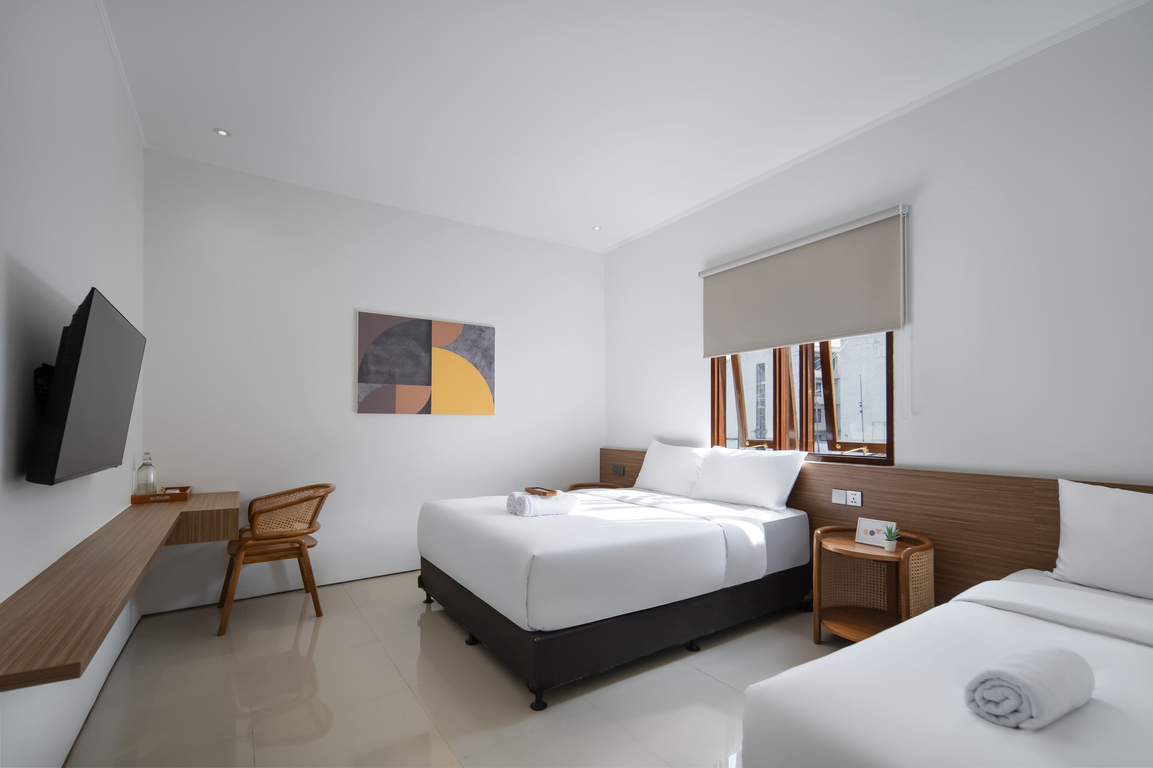 A modern hotel room with a bed, a desk, a chair, a TV, and a window with a view.