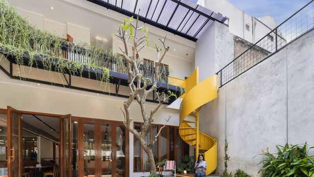 Un edificio moderno con una escalera espiral, una piscina y un comedor.