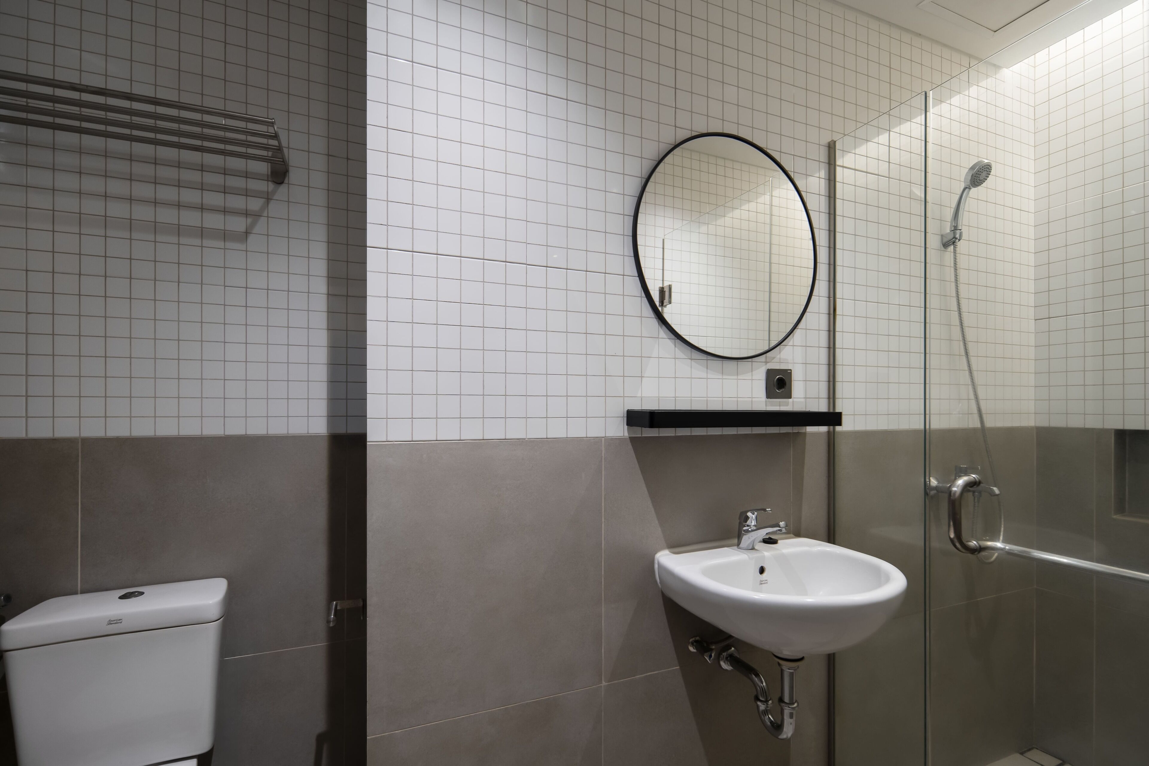 A bathroom with a toilet, a sink, a mirror, and a shower.