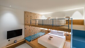 Habitación con literas, una pared de escalar, televisión de pantalla plana y piso de madera.