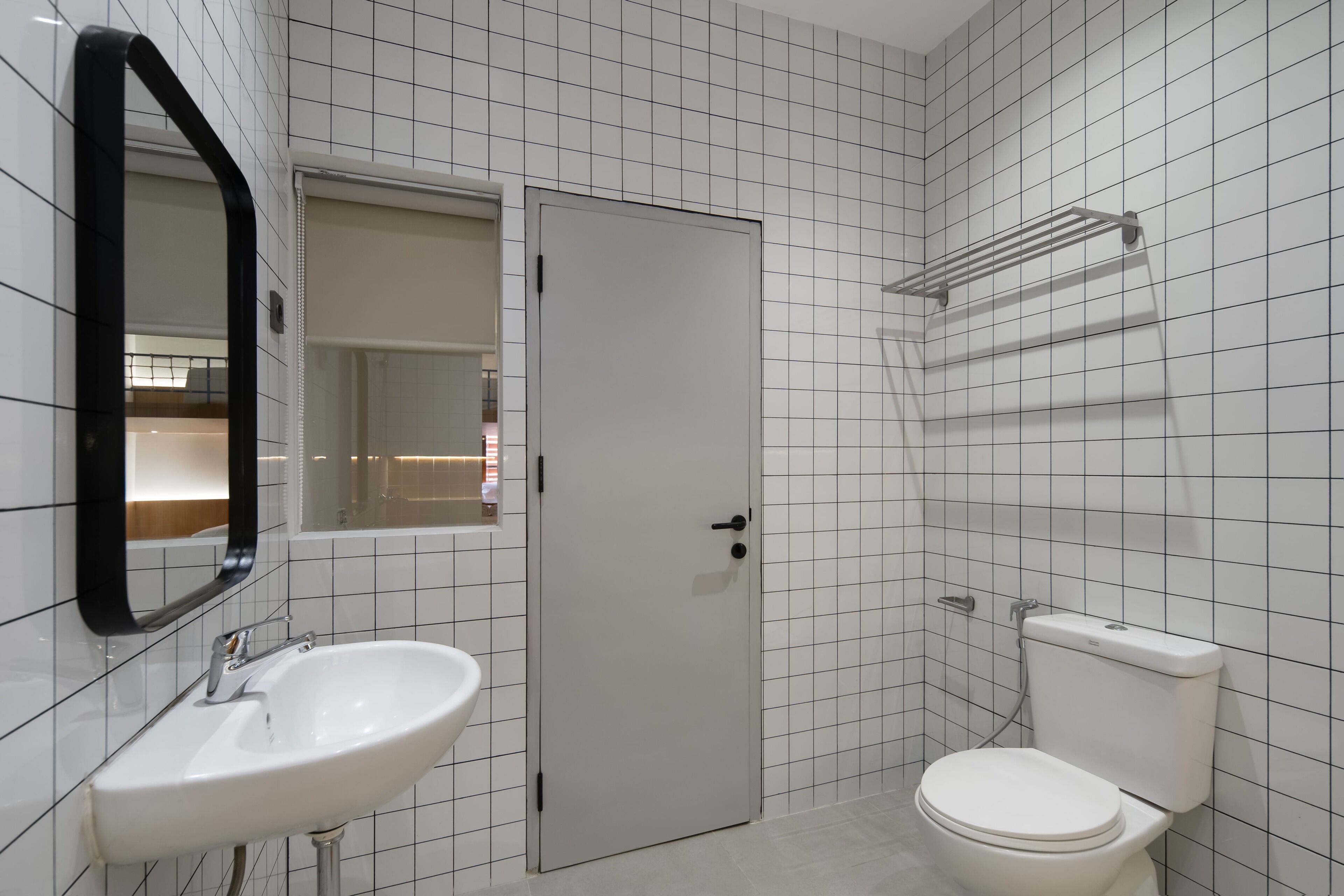 A bathroom with a white sink, a toilet, a door, and a mirror.