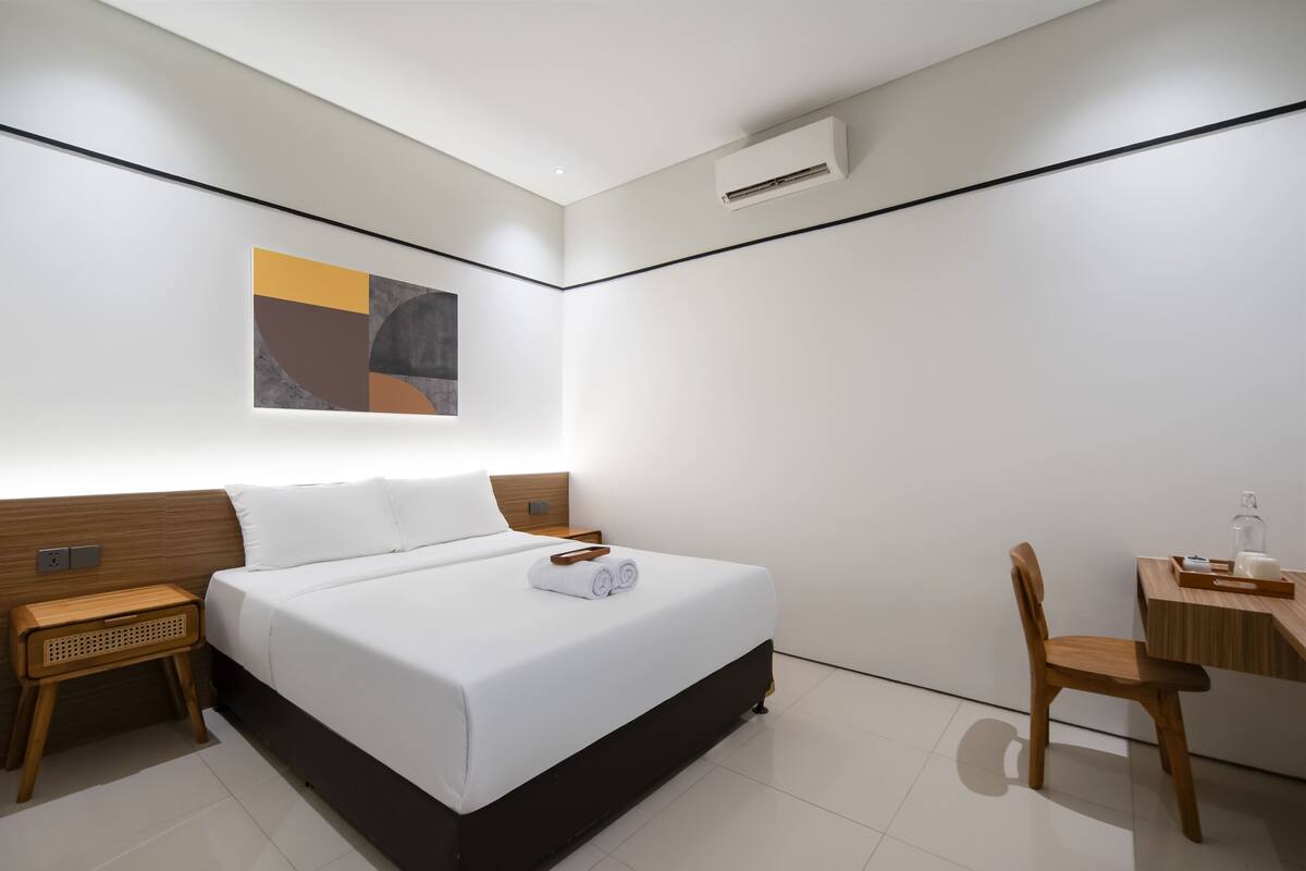 A modern hotel room with a large bed, bedside tables, a desk, and a chair.