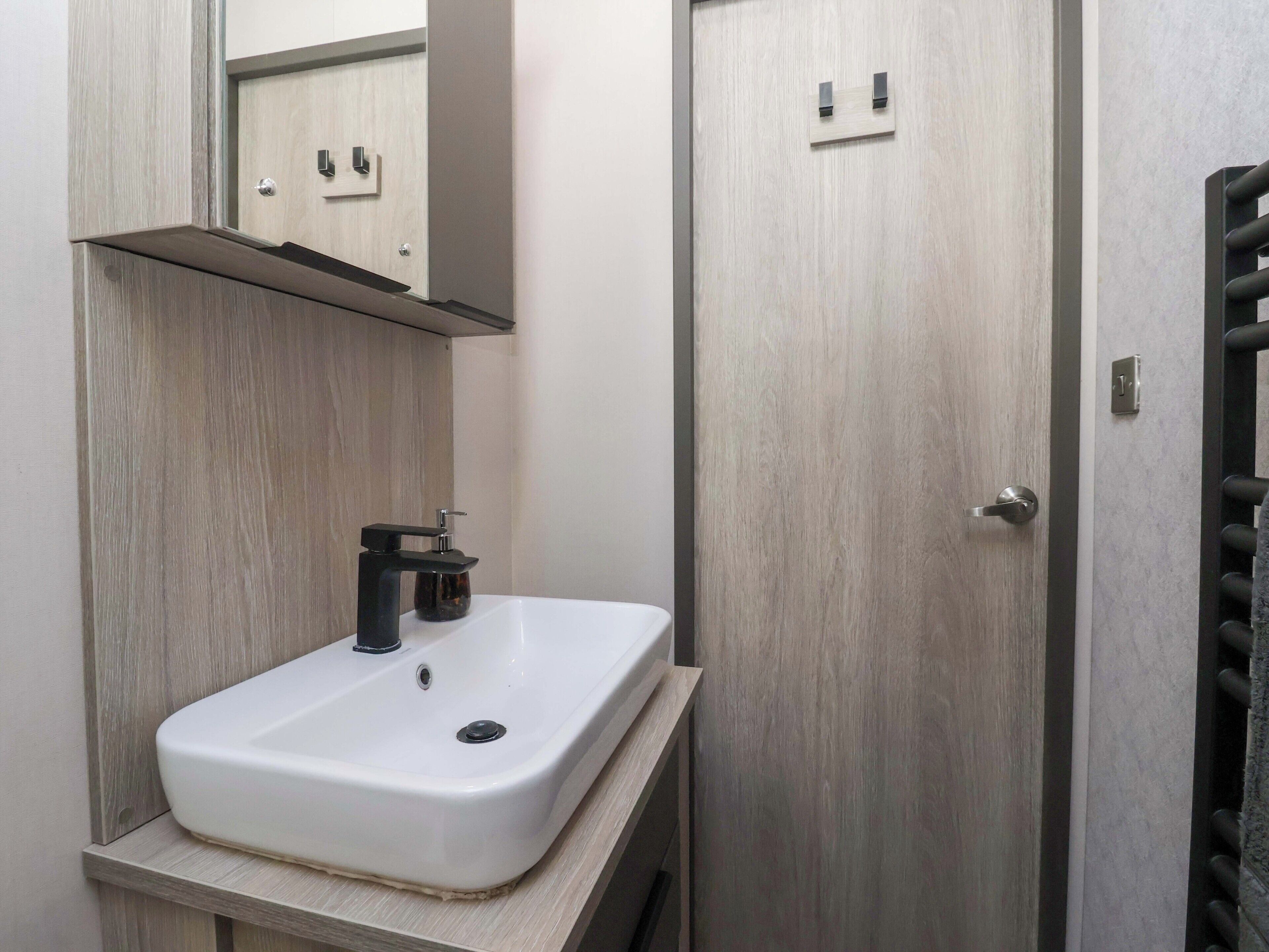 A bathroom with a white sink, a mirror, and a door with a handle.
