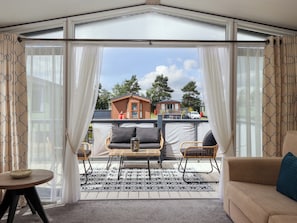A covered outdoor seating area with a table and chairs, a sofa, and a view of buildings in the background.