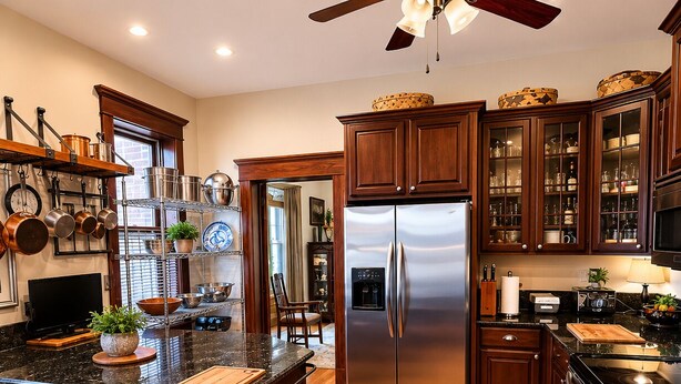 Una cocina con armarios de madera, un refrigerador de acero inoxidable y piso de madera.