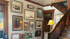 Una escalera con barandillas de madera, un tapete estampado y varias obras de arte enmarcadas en las paredes.