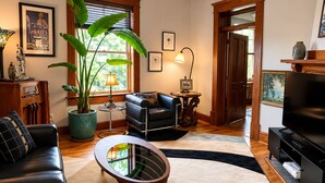 Una sala de estar con un sofá, una mesa de centro, una planta en maceta y un televisor.