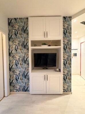 A living room with a flat-screen TV, white cabinets, and a patterned wall. - Lake Retreat (Brusimpiano)