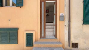 A building entrance with a door, steps, and a number plaque.